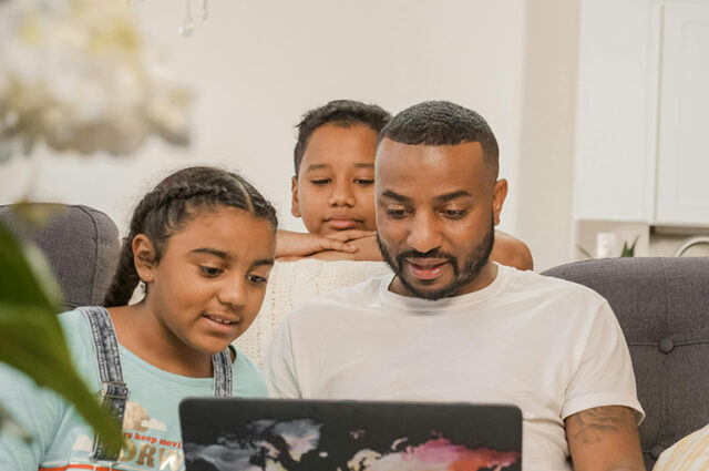 Man looking at laptop screen with two children, a boy and a girl