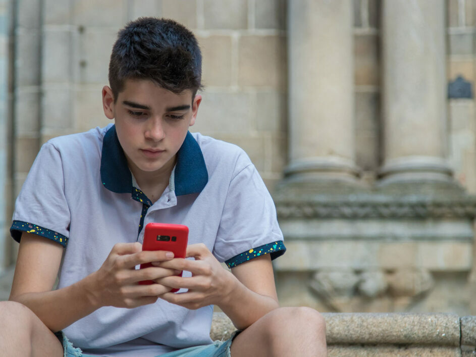 Teenage boy playing on phone