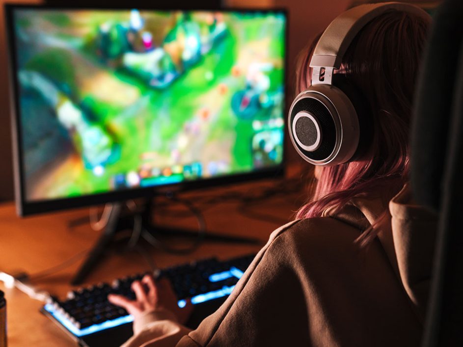 Girl playing video game on computer, with hands on keyboard