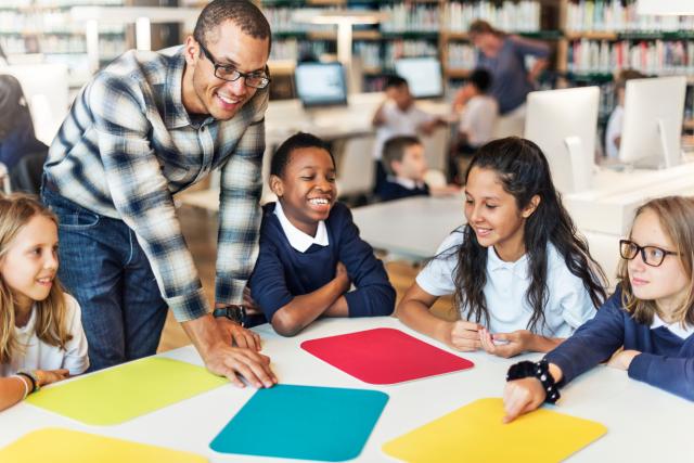 Children round a table with teacher